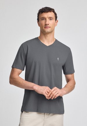 Grå v-hals t-shirt lavet af blødt stof, med korte ærmer og et lille logo på brystet. Designet er enkelt og klassisk.