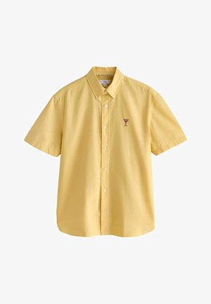 Chemise jaune à manches courtes avec boutons, avec un petit verre à cocktail rose brodé sur la poitrine gauche et un col boutonné.