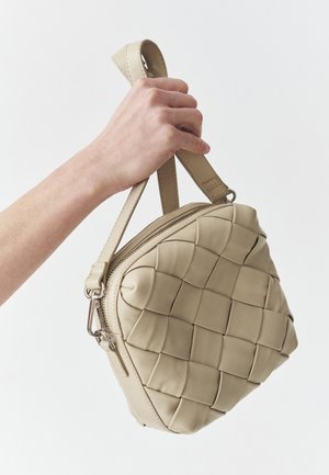 Beige Lederhandtasche mit geflochtenem Struktur, runder Form, oberem Reißverschluss und einem kurzen Henkel für einfachen Transport.