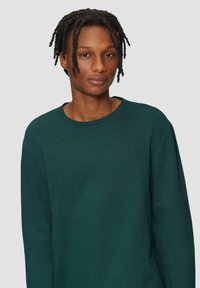 Groene sweatshirt met een ronde hals, lange mouwen en een zachte textuur. De pasvorm is casual, met minimale stiksels en geen zichtbare logo's.