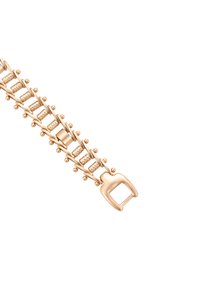 Primo piano di una chiusura di bracciale in oro con una catena decorativa e testurizzata e piccoli accenti sferici su uno sfondo bianco.