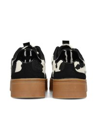 Sneaker in stampa mucca bianca e nera con tomaia testurizzata, suola piatta in gomma e linguetta sul tallone. Caratterizzati da materiali lisci e morbidi.