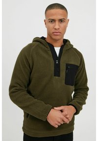 Pull-over en polaire vert olive avec une poche poitrine zippée noire, col zippé partiel, capuche et surface texturée. Conception à coupe régulière.