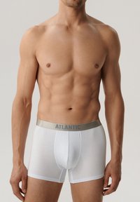 Białe majtki typu boxer wykonane z miękkiej bawełny, z metalicznie srebrnym paskiem w talii z nadrukiem "ATLANTIC". Wygodny krój i minimalistyczny design.