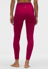 Legginsy z wysokim stanem w intensywnym odcieniu magenty, wykonane z elastycznego materiału, charakteryzujące się gładką fakturą i minimalną ilością szwów.