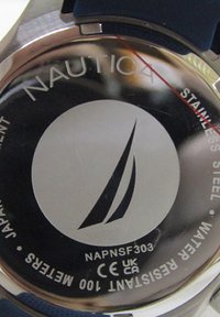Fondo de reloj de acero inoxidable plateado con el logo de Nautica de un velero, texto grabado y una correa de silicona azul visible por el lado.