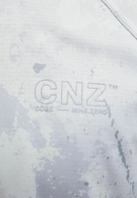 Valkoinen urheilukangas, jossa on hienovarainen tekstuuri, ja vaaleanharmaa "CNZ CORE — NINE.ZERO" -brändi näkyvästi esillä.