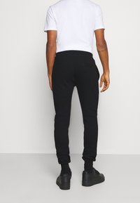 Svarta joggingbyxor i slim fit med elastiska mudd. Kombineras med svarta sneakers och en vit t-shirt med kort ärm.