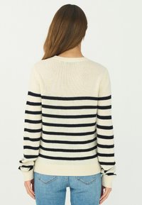 Gestreifter Pullover in Creme und Marineblau, mit langen Ärmeln, gerippten Bündchen und einem Rundhalsausschnitt. Stricktextur, lockere Passform und horizontale Streifen.