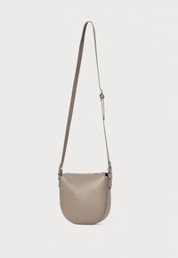 Beige kožená crossbody taška s kulatým tvarem. Má zipové uzavírání a nastavitelný ramenní popruh. Texturovaný povrch.