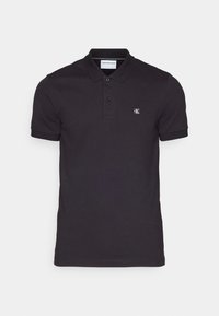 Polo noir à manches courtes avec patte de boutonnage à deux boutons, petit logo CK sur la poitrine gauche et col, présenté sur un fond blanc uni.