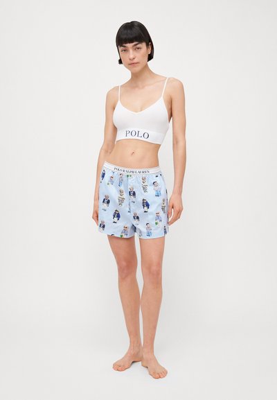 White bra with "POLO" logo in navy, paired with light blue striped shorts featuring a cartoon bear pattern, elastic waistband.