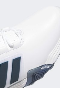 Λευκό αθλητικό παπούτσι με λείο δερμάτινο επάνω μέρος, υφασμάτινες μπλε ναυτικές λεπτομέρειες και διακριτικό με το λογότυπο "ADIPOWER" στη πλευρά.