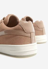 Helle rosa Sneakers aus Wildleder und Lackleder, mit einer weißen Sohle und glatter Textur, die durch markante Nähte und Akzente hervorgehoben werden.