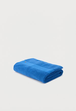 Serviette de bain bleue pliée avec un motif rayé texturé sur un fond clair uni.