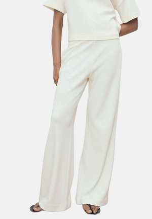 Bredde bukser i blødt cremefarvet stof, med en afslappet pasform og glat tekstur. Parret med en matchende cropped top.