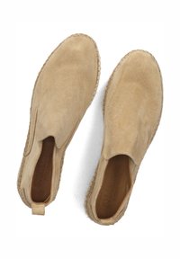 Beige suède instap schoenen met een ronde neus, elastische zij-inzetten en geweven jute details langs de zool. Gladde textuur.