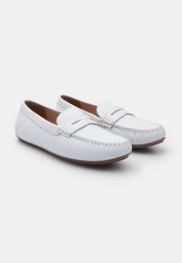 Valged nahast loafers, millel on mokassiini õmblus, lame pruun välistald ja sile tekstuur, kaunistava rihmaga üle ääre.
