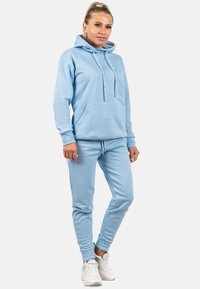 Felpa blu chiaro con cappuccio, tasca frontale e lacci, abbinata a pantaloni jogger tapered coordinati con polsini elasticizzati.
