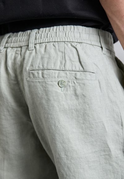 Helle grüne Leinen-Shorts mit einem elastischen Taillenbund, Seitentaschen und einer einzigen Gesäßtasche mit Knopfverschluss.