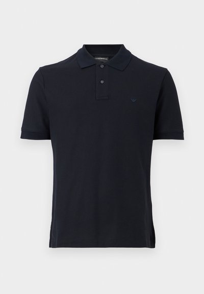 Μαύρο κοντομάνικο πόλο πουκάμισο με δύο κουμπιά και μικρό κεντητό λογότυπο στο αριστερό στήθος, παρουσιασμένο σε απλό φόντο.