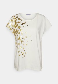Vit kortärmad T-shirt med löst spridda guldfolieprickar koncentrerade på den övre vänstra sidan och axeln.