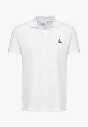 Polo blanc à manches courtes avec col et deux boutons, avec un petit logo vert de palmier et de crocodile sur la poitrine gauche.