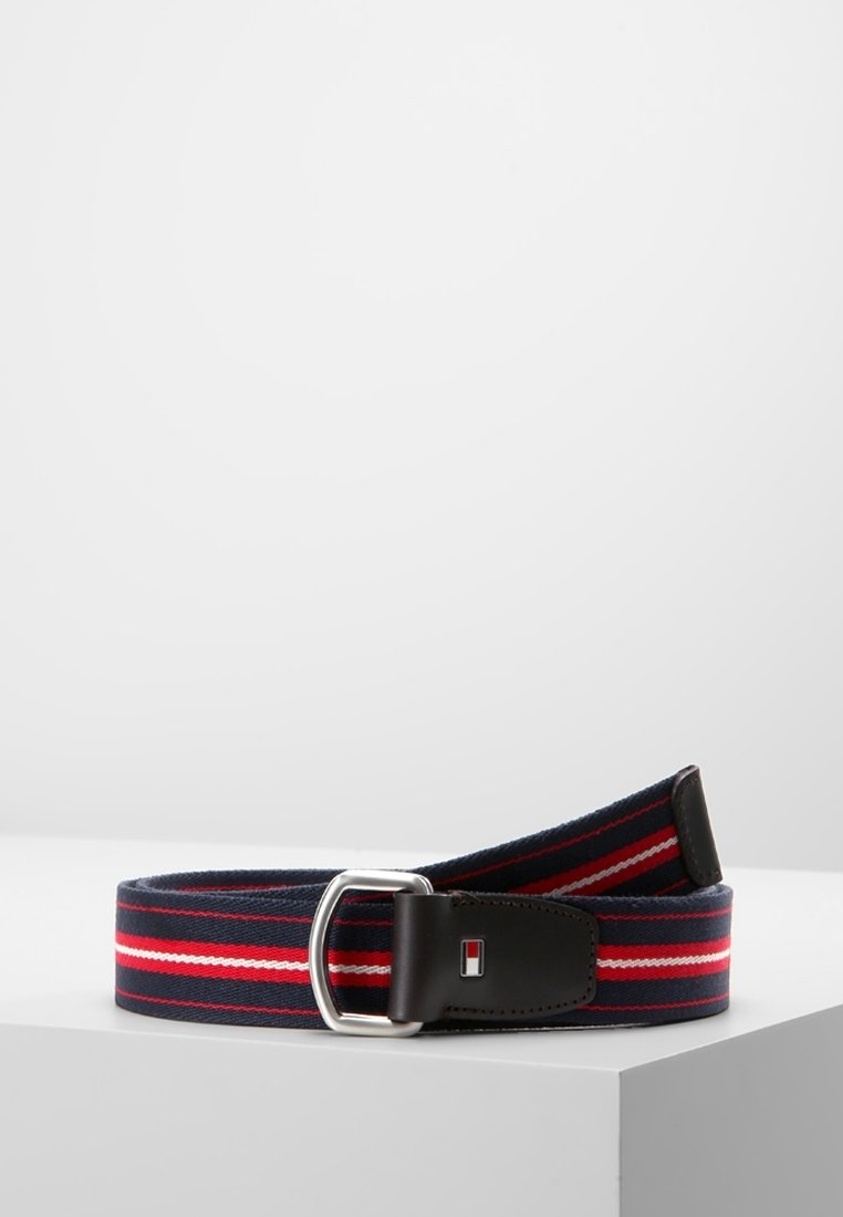 Granatowy materiałowy pasek z czerwono-białymi paskami, srebrną metalową klamrą i czarną skórzaną końcówką z małym prostokątnym logo.