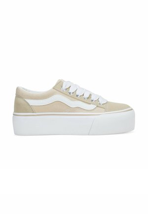 Zapatillas de lona beige con acentos en blanco, cordones planos y una suela de plataforma blanca gruesa. Presentan un diseño de ola distintivo en el lateral.