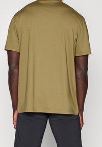 Koszulka polo z krótkim rękawem w kolorze oliwkowym, wykonana z miękkiej tkaniny, z klasycznym kołnierzykiem i luźnym krojem dla wygody.