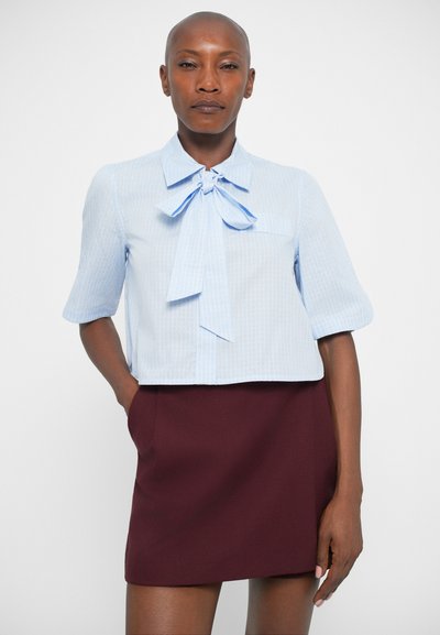 Lichtblauw, kort mouwblouse met een strikdetail bij de kraag, voorzien van een subtiele gestreepte patroon, gecombineerd met een bordeauxrode rok.