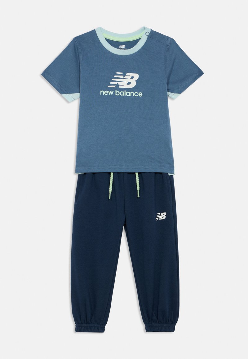 Blauw New Balance kindert-shirt met korte mouwen en logo, gecombineerd met bijpassende marineblauwe joggingbroek met koord en enkelmanchetten.