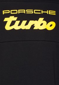 Tela negra con el texto en negrita "Porsche turbo" impreso en amarillo.
