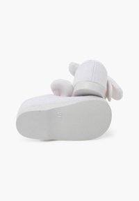 Calzado de tela blanca con un upper texturizado, puntera redonda y una suela de goma blanca gruesa. Presenta suaves acentos en forma de orejas en la parte trasera.