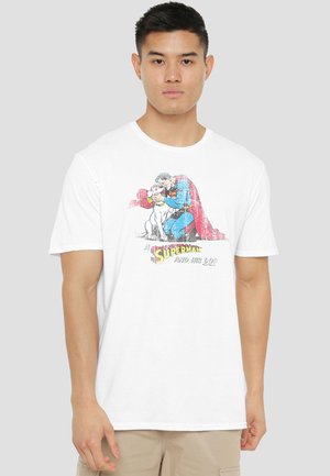 Man wearing white T-shirt with graphic of Superman kneeling and hugging a dog, text reads "Superman and His Dog."