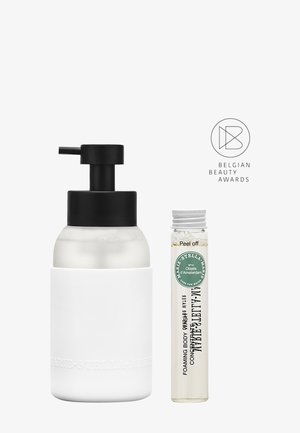 Distributeur en céramique blanche avec une pompe noire à côté d'un tube en verre transparent contenant un liquide. Les deux présentent la marque "MARIE-STELLA-MARIS".