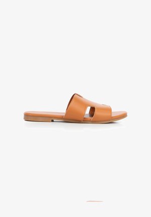 Tan leather slip-on sandal with cut-out design, flat sole, and open toe, shown on a white background.