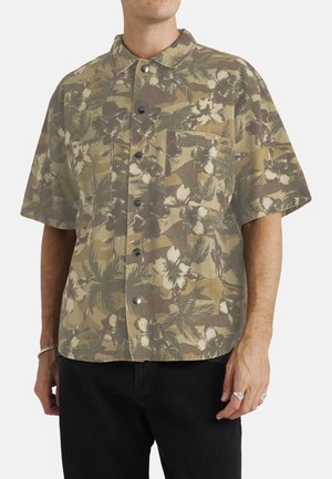 Short-sleeve shirt made of lightweight fabric, featuring a green, brown, and cream floral pattern, with a button-down front and a chest pocket.
