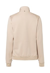 Beige jas met een staande kraag, een soepele textuur en ritsmanchetten. Heeft subtiele panelen op de schouders en een verborgen rugzakje.