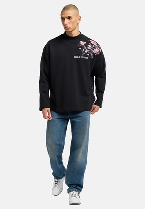 Sort sweatshirt med blomsterbroderi i pink, ribbet halsudskæring, løst design. Sættes sammen med lyseblå jeans og hvide sneakers.