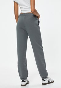 Grijze joggingbroek met een relaxed fit, elastische tailleband en geribbelde manchetten. De stof lijkt zacht; er zijn zijzakken inbegrepen.