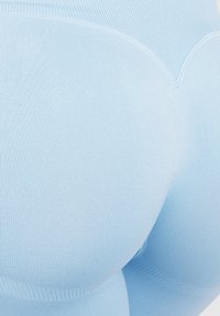 Jasnoniebieskie legginsy wykonane z elastycznego, prążkowanego materiału. Gładka faktura z dopasowanym krojem i konturowymi szwami dla efektu modelowania.