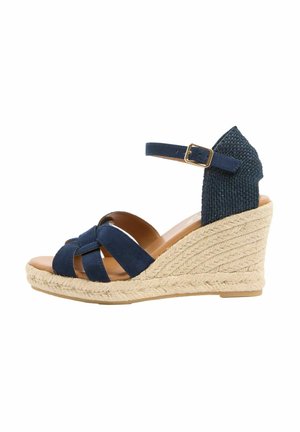 Marineblaue Keilsandalette mit geflochtenem Jute-Plateau, Knöchelriemen mit Schnalle und geflochtenem Fersenriemen.