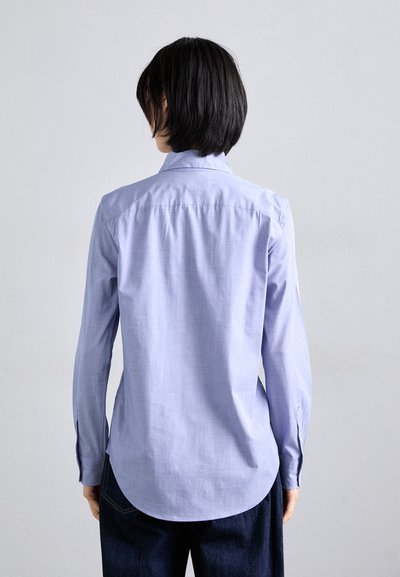 Light blue long-sleeve shirt with a collar, back yoke, and curved hem. The fabric appears smooth with a subtle texture.