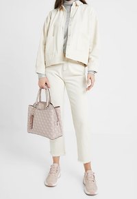 Kremowa kurtka sztruksowa, szary sweter, białe dżinsy, torba w różowe wzory oraz jasnoróżowe sneakersy z akcentami. Krótkie postrzępione nogawki dżinsów.