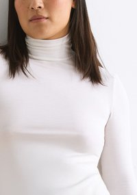 White long-sleeve turtleneck made of smooth, stretch fabric, featuring a close-fitting design and folded collar.