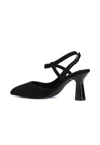 Pump slingback in suede nero con punta affusolata e cinturino alla caviglia regolabile. Presenta un tacco geometrico lucido per un'altezza aggiuntiva.