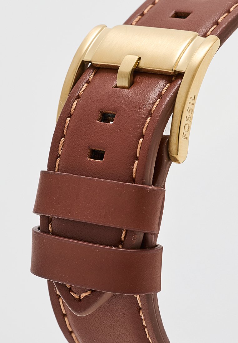 Correa de reloj de cuero marrón con hebilla de metal dorado, costura en contraste y múltiples agujeros de ajuste para el tamaño.