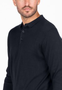 Navyblaues Langarm-Poloshirt aus weichem Material, mit einem Kragen und drei schwarzen Knöpfen. Glatte Textur mit tailliertem Design.