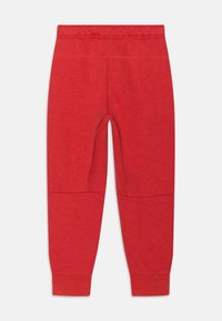 Rote Jogginghose mit weichem Stoff, elastischem Bund, schmal zulaufenden Beinen und Kniepaneelen. Schlichte Design ohne zusätzliche Verzierungen.